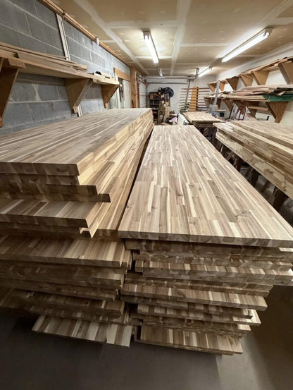 Long acacia butcher block countertop slabs stacked in the shop