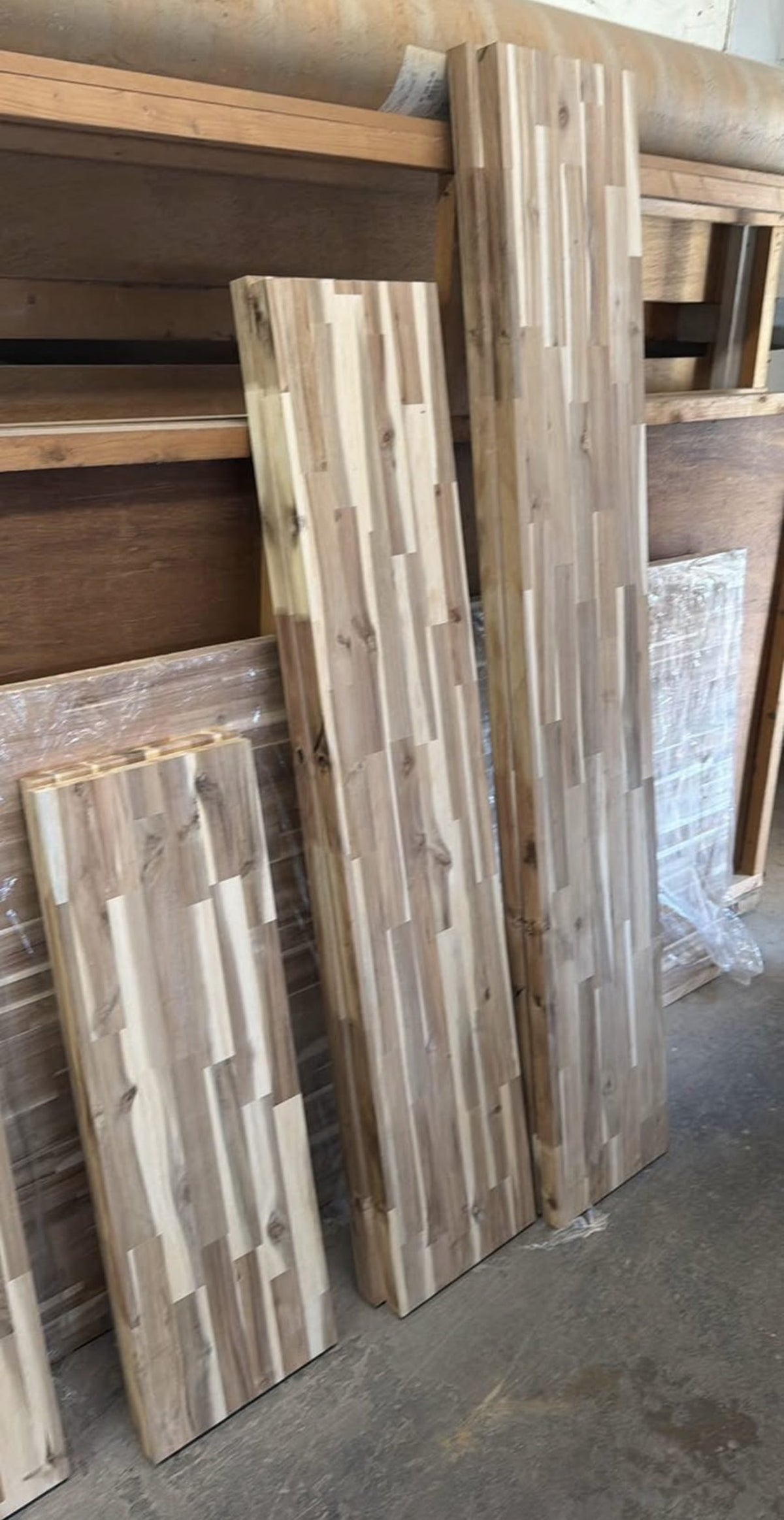 Acacia butcher block slabs leaning against a rack in the shop